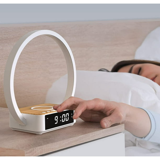 Elegante reloj despertador junto a la lámpara en la mesa manso para  despertar