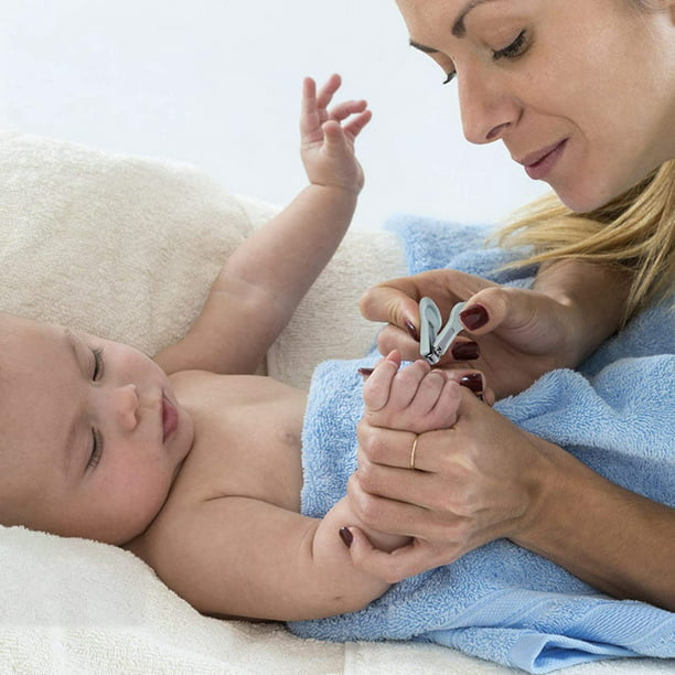 Mamá corta las uñas del bebé con tijeras especiales para niños cerca de  manicura para recién nacidos de fondo gris