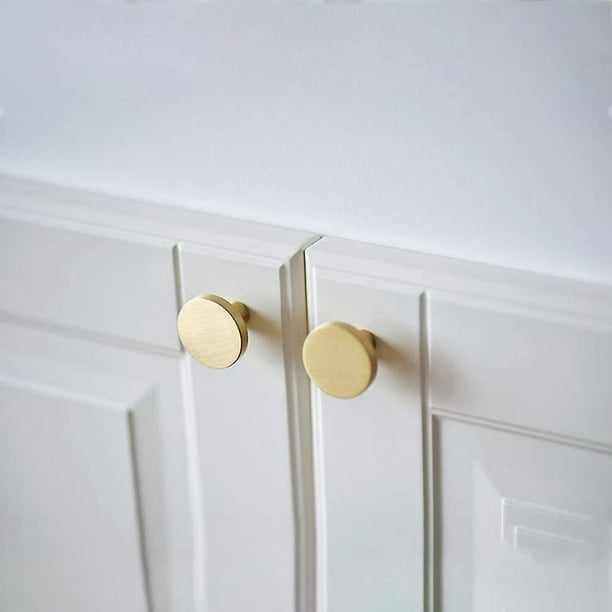 Un armario blanco con tiradores dorados y una puerta de madera.